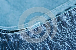 Texture of blue genuine leather sewn with hand made sewing stitch. For fashionable modern background