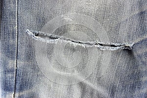 Texture of blue jeans with frayed hole