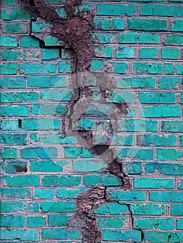 Texture of a brick wall with cracks in turquoise color. The destroyed ancient wall is turquoise. Brick background copy space