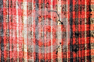 The texture of a checkered red-black cloth stained with black spots