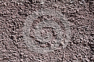 Texture of a concrete wall in brown color with an uneven surface.