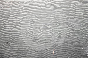 Texture created in the sand of the beach, covered by the puddled water, calm and shallow at low tide.