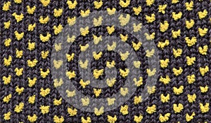 Texture of crocheted dark fabric with simple yellow polka dot pattern