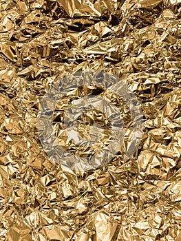 Texture of crumpled golden foil. Shiny festive background. Metallized paper.