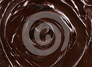 Texture of dark chocolate icing swirl close up. Food background