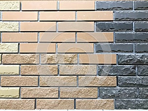 Texture of a decorative wall of two-tone building brown and black textured embossed brick with seams. The background