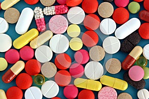 Texture from different medicines, tablets and capsules on a blue background.