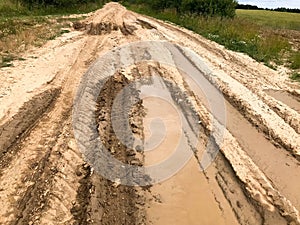 Texture of a dirty bad dirt road dirt road with puddles and clay drying mud with cracks and ruts. Off-road. The background