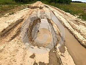 Texture of a dirty bad dirt road dirt road with puddles and clay drying mud with cracks and ruts. Off-road. The background