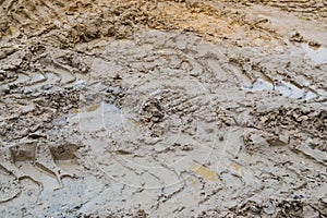 Texture of a dirty bad dirt road dirt road with puddles and clay drying mud with cracks and ruts. Off-road. The background