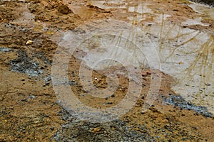 Texture of a dirty bad dirt road dirt road with puddles and clay drying mud with cracks and ruts. Off-road. The background