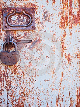 The texture of the door and the lock of the old rusty red metal