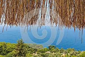 Texture of dry straw on the roof of view with a blue sea background. holiday background