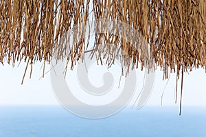 Texture of dry straw on the roof of view with a blue sea background. holiday background