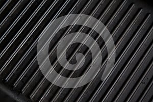 Texture of empty black cast heavy iron grill pan, modern kitchen equipment