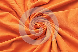 The texture of the fabric swirling in a whirlpool. Orange knitwear. Waste recycle. New clothes. Salon of tailoring.