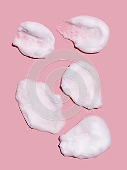 Texture of foam or mousse strokes on a pink background. Soap, shower gel, foam shampoo. Skin care. View from above