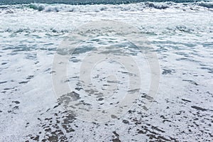 Texture of foamy wave on the beach, background