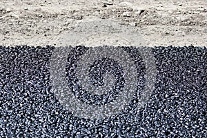 Texture of fresh hot black asphalt is laid on the new road near the roadside