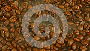 Texture of freshly coffee beans with dissipating steam. Lots of roasted beans for preparation of fragrant drink. Close