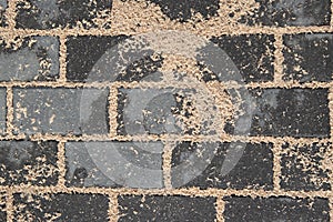 Texture of freshly laid graphite paving stones - close-up of a fragment of the pavement during sand siltation