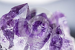 Texture of gemstone lilac Amethyst closeup as a part of cluster geode filled with rock Quartz crystals.