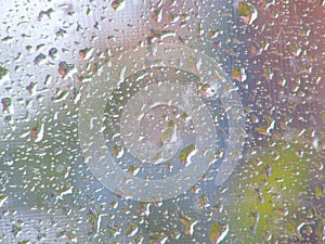 Texture of glowing raindrops on the glass after the rain, background blurry colored spots