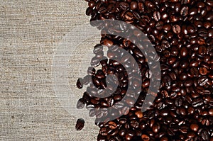 Texture of a gray canvas made of old and coarse burlap with coffee beans on it