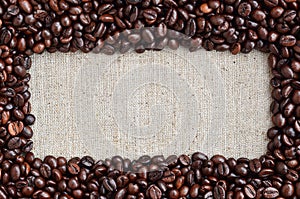 Texture of a gray canvas made of old and coarse burlap with coffee beans on it