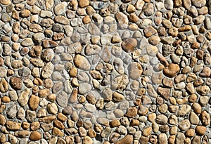 Texture of a gray concrete wall with small brown rounded stones