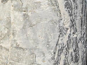The texture of a gray marble stone with veins, cracks and inclusions