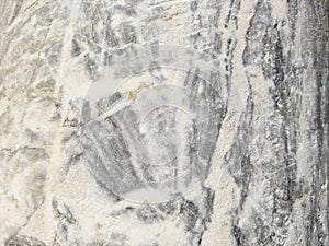 The texture of a gray marble stone with veins, cracks and inclusions
