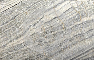 The texture of a gray marble stone with veins, cracks and inclusions