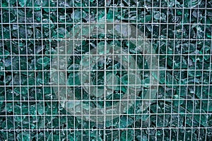 Texture of gray metal grate and green pieces of glass