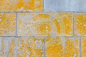 The texture of a gray stone wall with a yellow paint