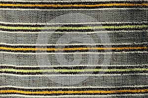 Texture of handmade carpet made on hand-loom, pattern of yellow, orange and black vertical lines dividing grey vertical fields