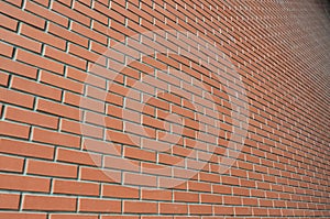 The texture of a high brick wall from a many rows of red bricks stretching into perspectiv