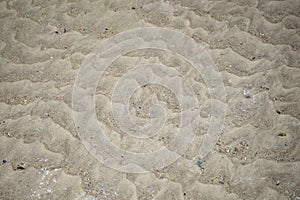 Texture of light beige sand with small pebbles under water