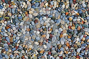 Texture of lots of small colorful pebbles on the ground.