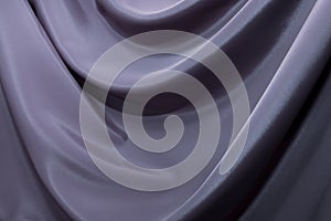 The texture of a luxurious smooth fabric in blue, purple with folds and waves. Blue fabric, material