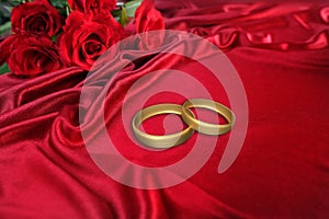 Texture of luxury red silk fabric, background with waves and drapery for fashion design, gold wedding rings. bouquet of roses,