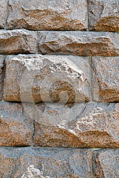 Texture made of huge large sturdy, strong, raised, convex, natural stone, granite crooked wall with seams and cracks. background