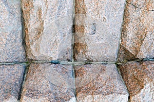 Texture made of huge large sturdy, strong, raised, convex, natural stone, granite crooked wall with seams and cracks. background