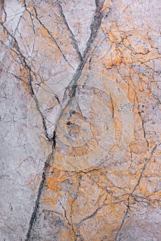 The texture of a marble slab with a pink-brown tint with cracks and veins