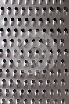 Texture metallic silver surface with small holes, stainless steel grater for vegetables close-up. Background backdrop textured