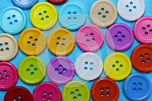 Texture of multi-colored buttons laid out on a blue surface