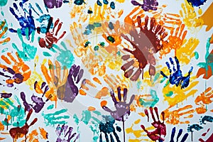Multi-colored prints of hands smeared with paint on a white wall