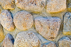 Texture of natural carved solid strong rough textured mineral gray brown stone cobblestone walls of the rock. Stone background