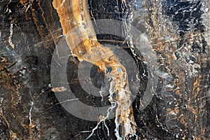 Texture of natural gray-black quartz stone with orange mineral inclusions