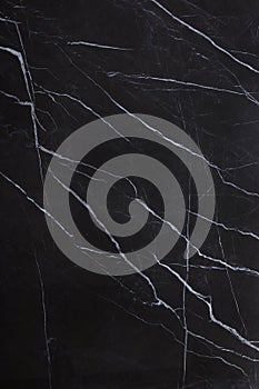 The texture of natural stone is black marble with patterns and white stripes, the stone is called Nero Marquina photo